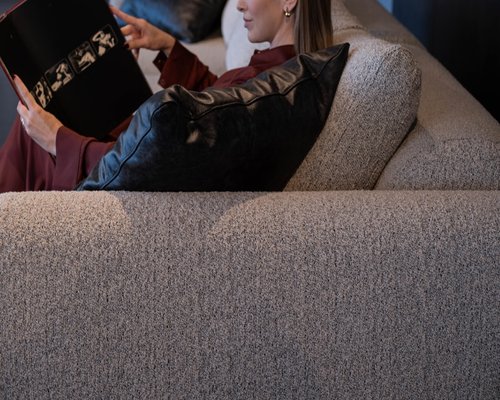 A person resting calmly on a sofa reading a book in a cozy room