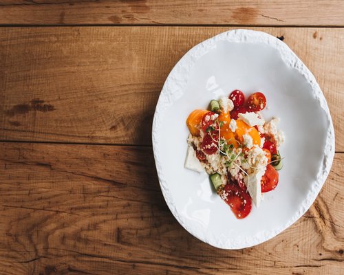 A healthy balanced lunch plate with fresh vegetables and grains on a wooden table