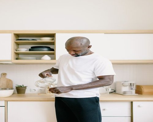 A person pouring a glass of fresh water in a bright kitchen