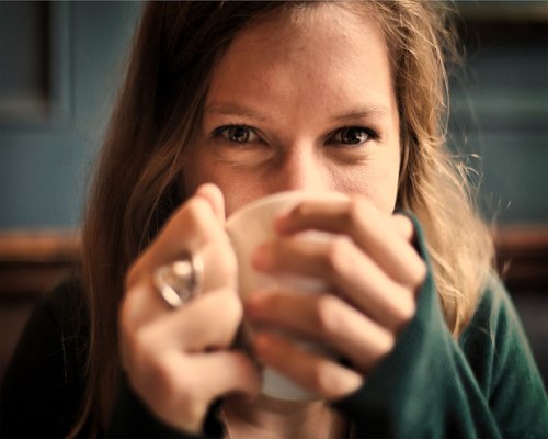 Colombian woman smiling while relaxing with a cup of coffee in a bright modern apartment